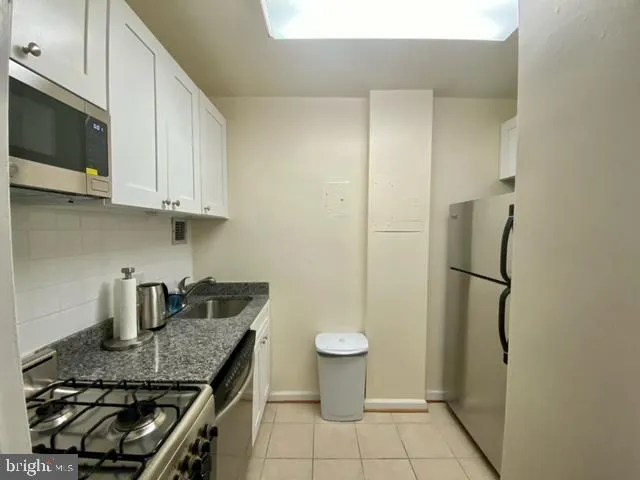 a kitchen with a granite countertop sink a stove and refrigerator