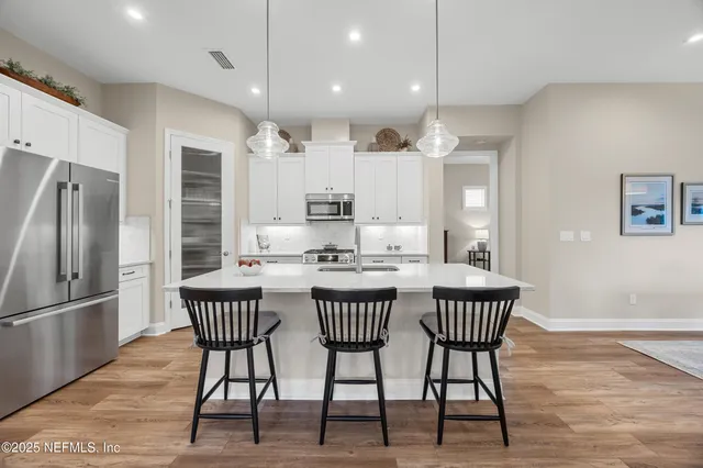 a kitchen with stainless steel appliances granite countertop a dining table chairs refrigerator and microwave