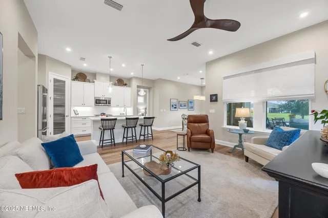 a living room with furniture kitchen view and a large window