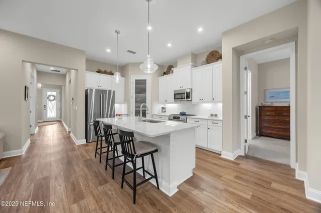 a kitchen with stainless steel appliances kitchen island granite countertop a table chairs refrigerator sink and cabinets