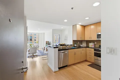 a kitchen with stainless steel appliances kitchen island granite countertop a stove and white cabinets