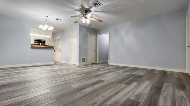 a view of empty room with wooden floor and fan