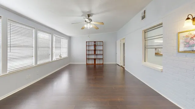 a view of an empty room with a window and wooden floor