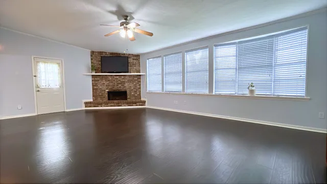 an empty room with windows fireplace and wooden floor