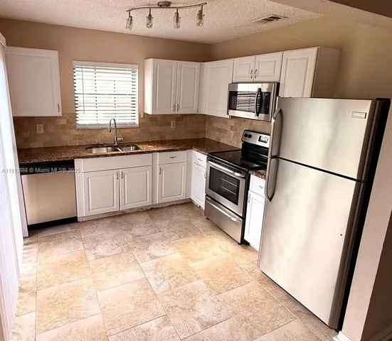 a kitchen with granite countertop a refrigerator and a sink