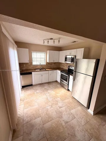 a kitchen with granite countertop a refrigerator and a stove top oven
