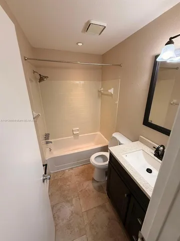 a bathroom with a sink vanity mirror and bathtub