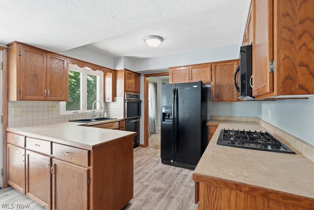136 Pinehurst Road Munroe Falls, OH 44262 - Photo 14 of 48 Kitchen featuring wood cabinetry, light countertops, wood-finish flooring, a double wall oven, and a black side-by-side refrigerator