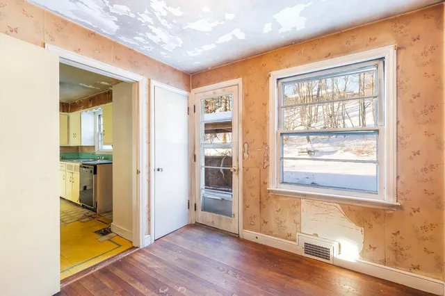 an empty room with wooden floor and windows