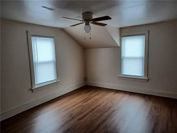 a view of an empty room with a window and wooden floor