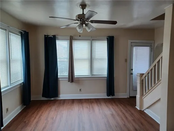 an empty room with wooden floor fan and windows