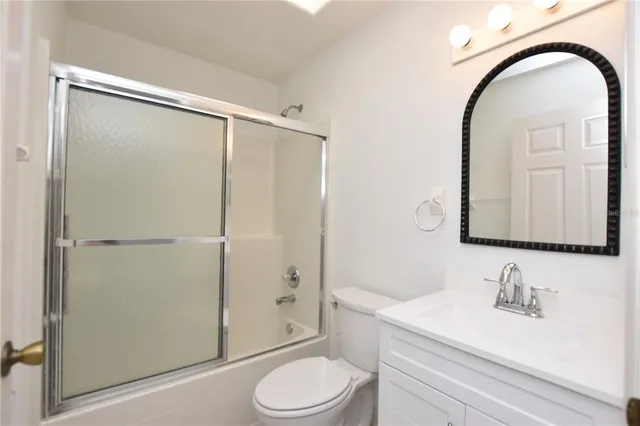 a bathroom with a toilet a sink a mirror a shower and vanity