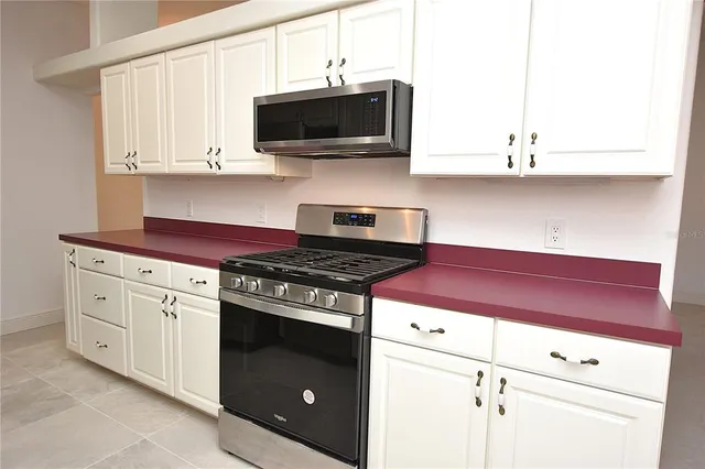 a kitchen with stainless steel appliances white cabinets and a stove top oven