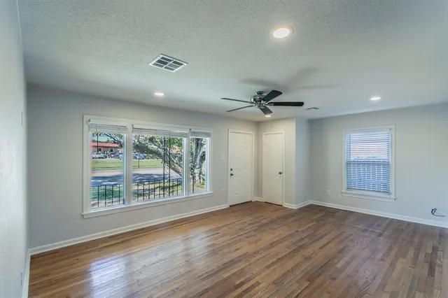 an empty room with wooden floor chandelier and windows