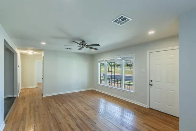 a view of an empty room with wooden floor and a window