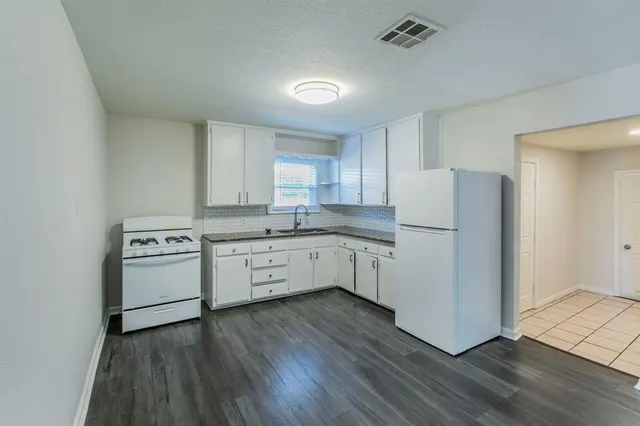 a kitchen with a white cabinets and wooden floor