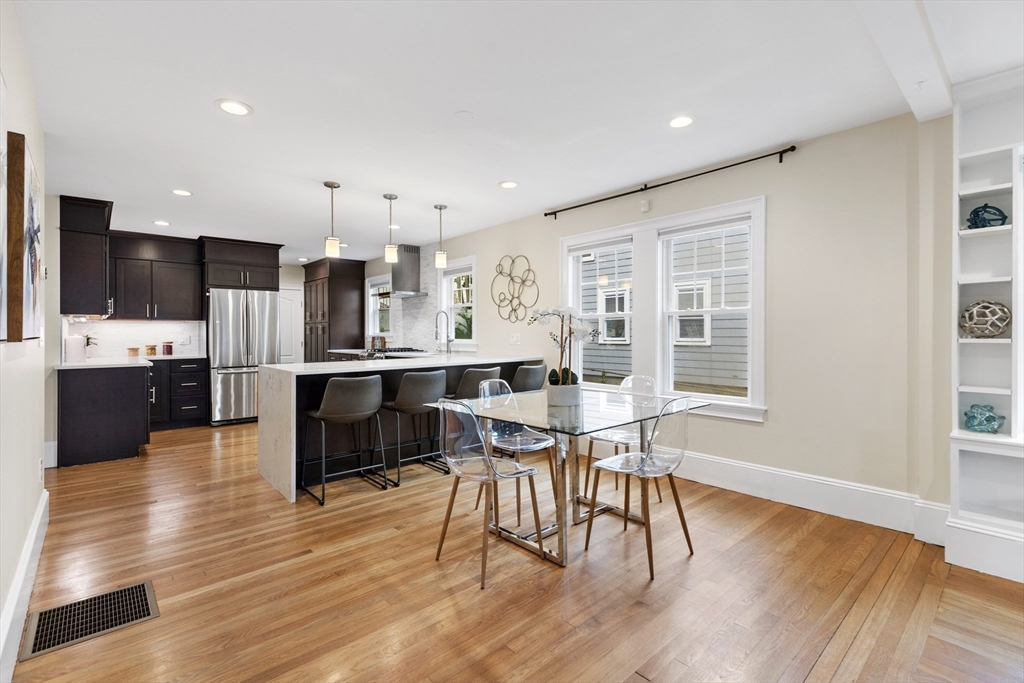 47 Fuller Road, Unit 47 Watertown, MA 02472 - Photo 7 of 21 a open kitchen with stainless steel appliances kitchen island granite countertop a stove a refrigerator a sink a dining table and chairs with wooden floor