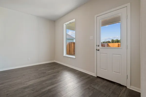 an empty room with wooden floor mirror and windows