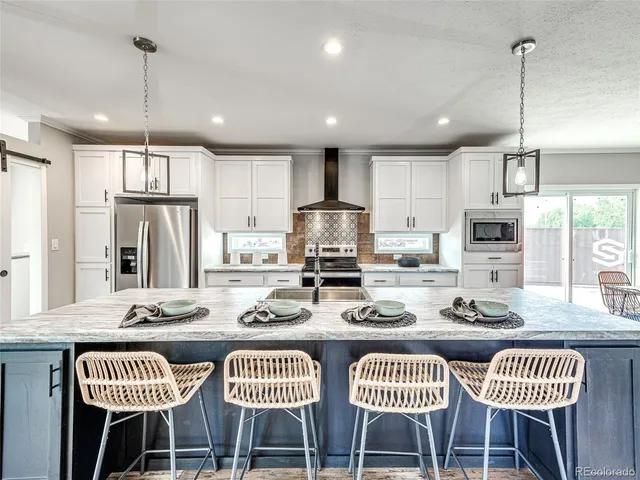 a kitchen with stainless steel appliances granite countertop a dining table chairs refrigerator and microwave