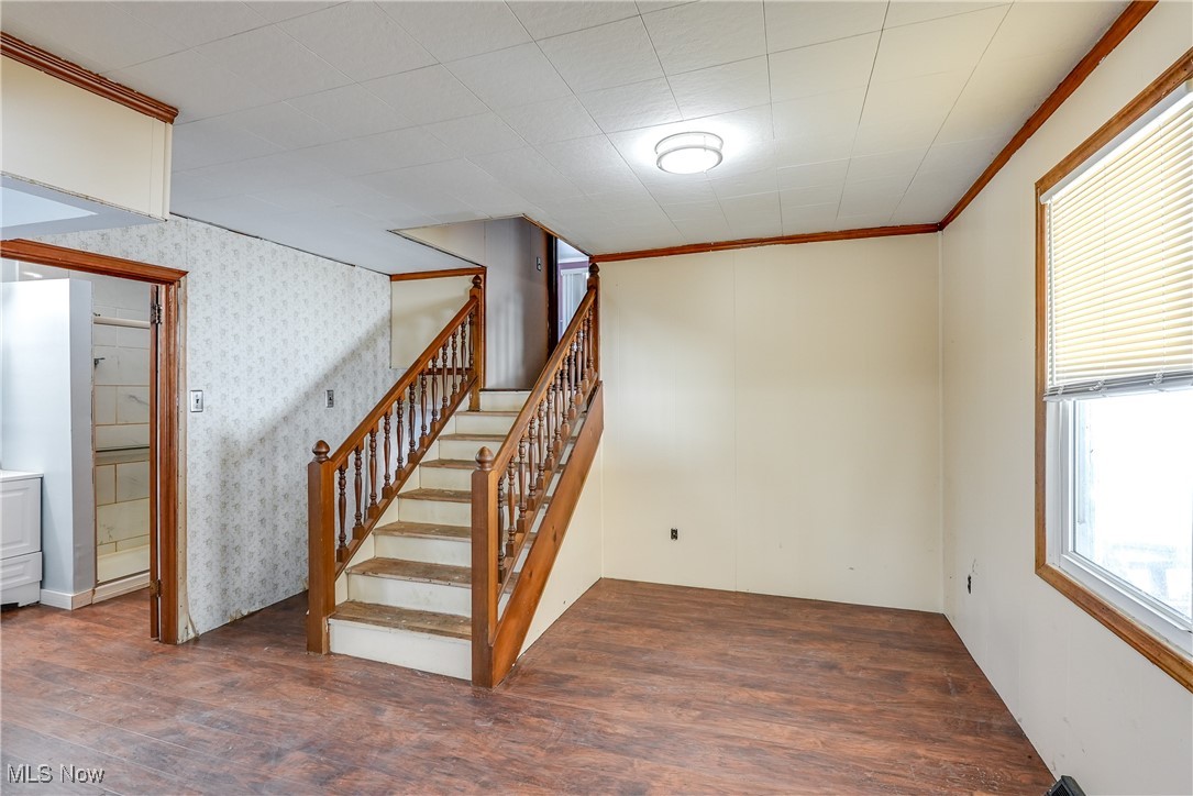 Stairs with wood-type flooring and crown molding