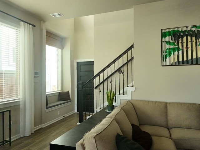 4910 Anders Lane Rosharon, TX 77583 - Photo 2 of 3 Open-concept living area with high ceilings, large windows, a built-in window seat, and modern iron stair railing.