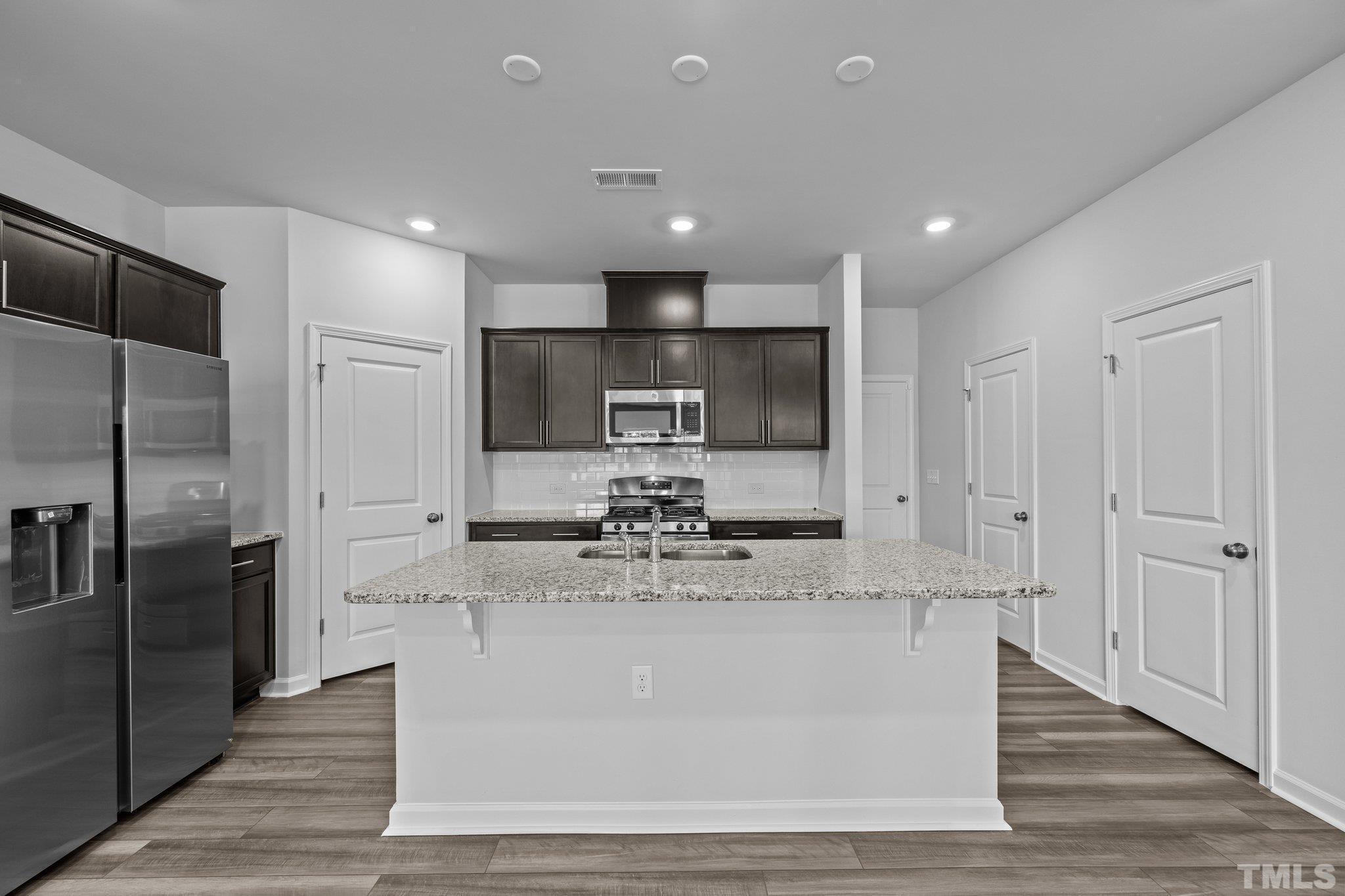5106 Anamosa Street Raleigh, NC 27610 - Photo 20 of 49 a large kitchen with stainless steel appliances granite countertop a large counter top and a refrigerator