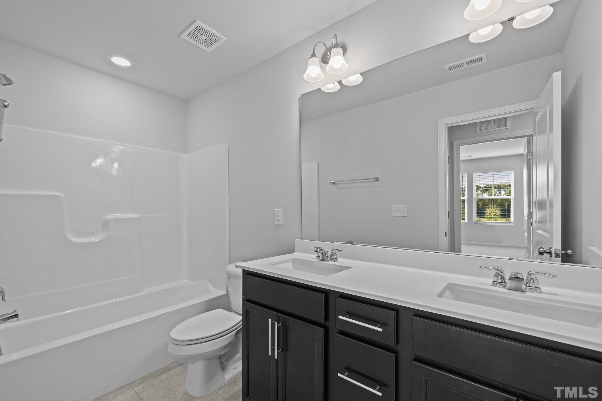 5106 Anamosa Street Raleigh, NC 27610 - Photo 9 of 49 a bathroom with a double vanity sink toilet mirror and bathtub
