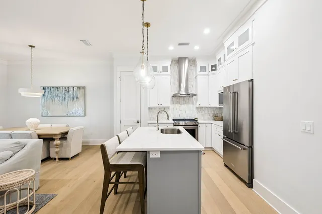 a kitchen with stainless steel appliances kitchen island a table chairs in it and wooden floors