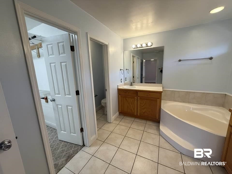 10428 South Side Loop Fairhope, AL 36532 - Photo 20 of 28 Bathroom featuring tile patterned flooring, a garden tub, vanity, and toilet