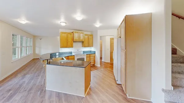 a kitchen with stainless steel appliances granite countertop a refrigerator a stove and a wooden floors