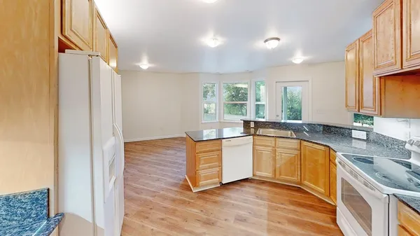 a large kitchen with stainless steel appliances granite countertop a sink stove and refrigerator