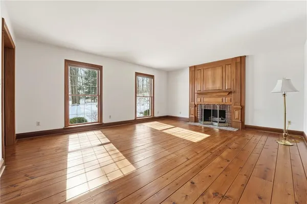 a view of empty room with fireplace and wooden floor