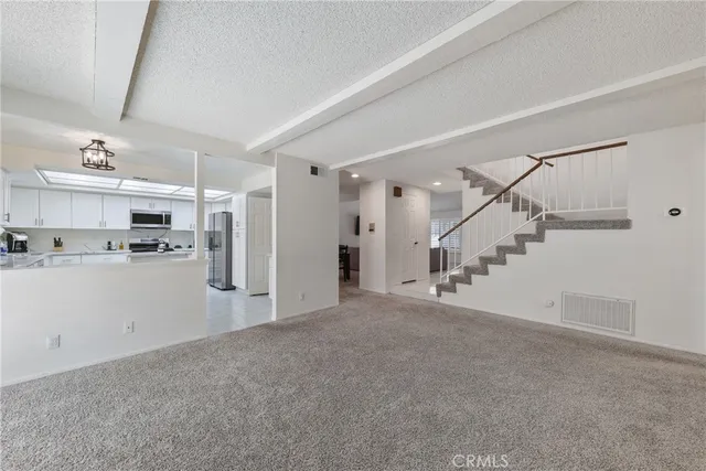 a view of a big room with staircase and kitchen view