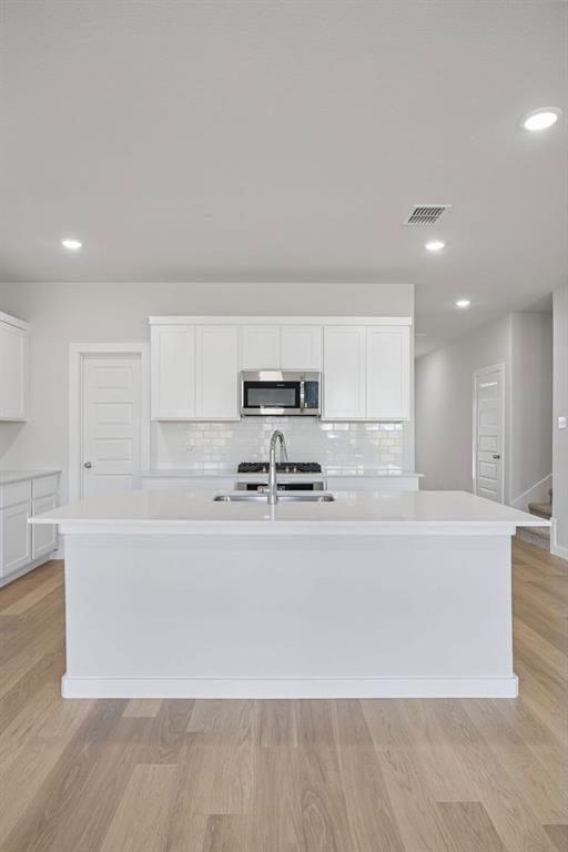 1472 Companero Street Haslet, TX 76052 - Photo 11 of 40 a large white kitchen with kitchen island a stove a sink a refrigerator and white cabinets