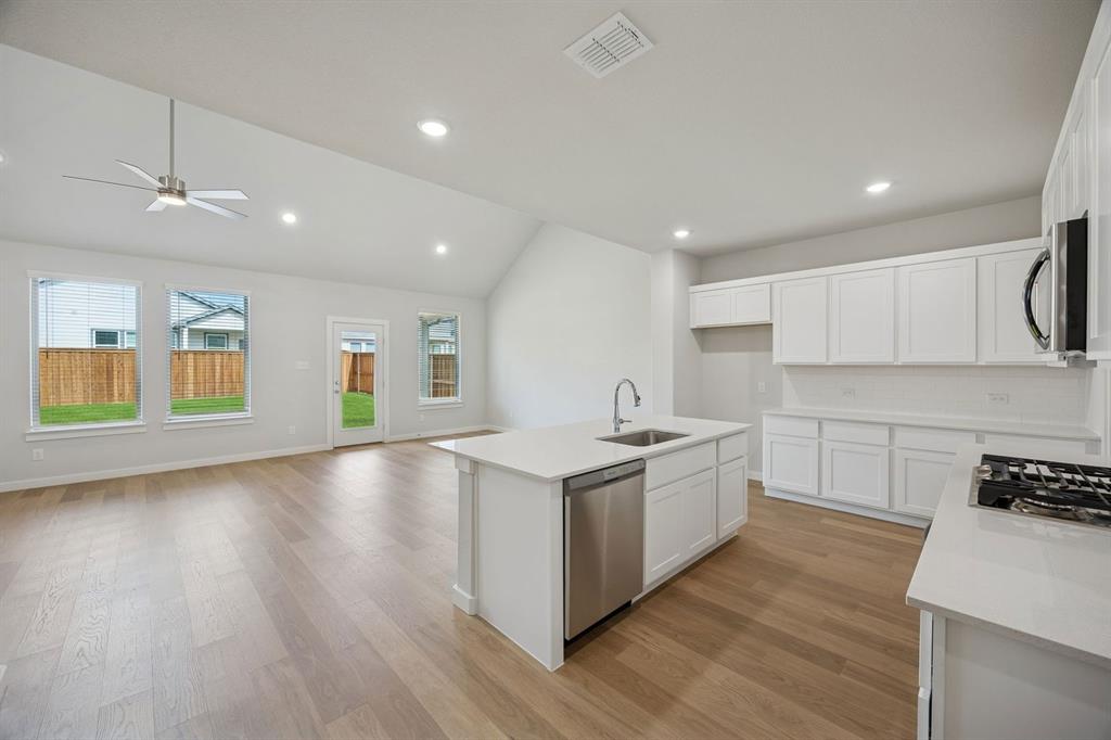 1472 Companero Street Haslet, TX 76052 - Photo 38 of 40 a large kitchen with stainless steel appliances granite countertop a lot of counter space and wooden floors