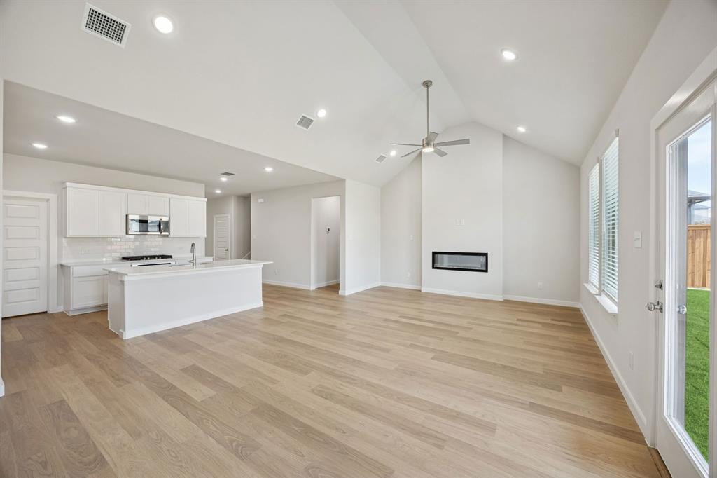 1472 Companero Street Haslet, TX 76052 - Photo 40 of 40 a large white kitchen with kitchen island a stove a sink dishwasher and a refrigerator with wooden floor