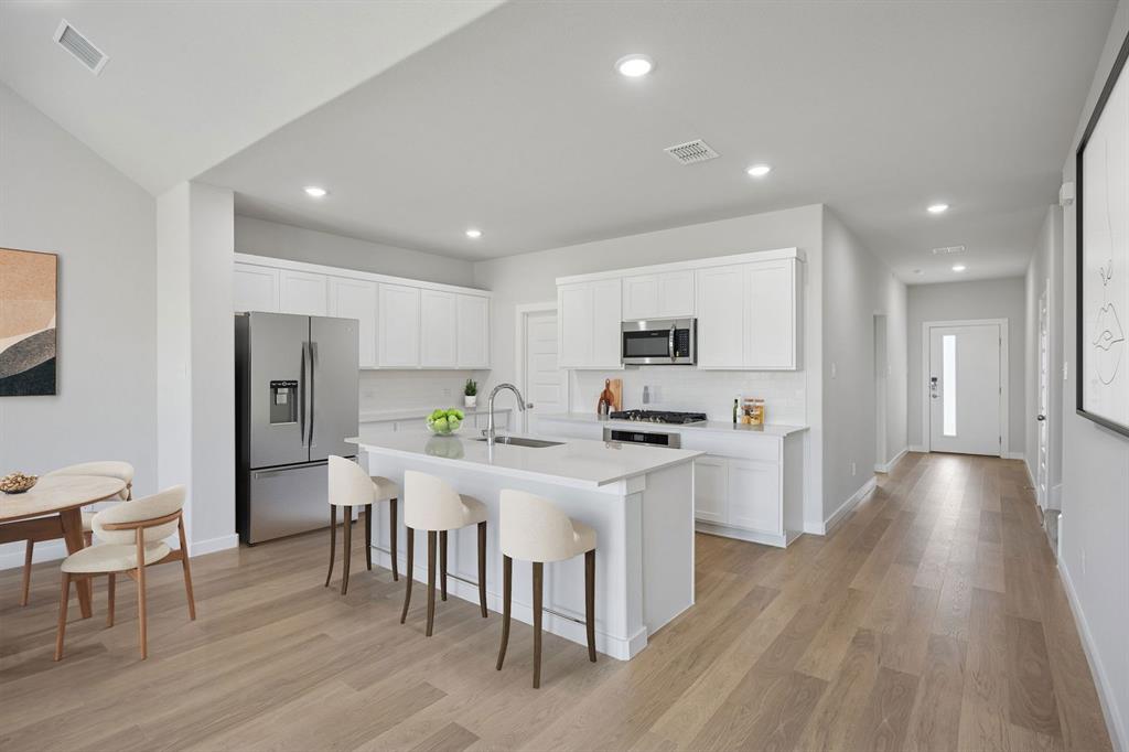 1472 Companero Street Haslet, TX 76052 - Photo 8 of 40 a kitchen with stainless steel appliances a dining table chairs refrigerator microwave and cabinets