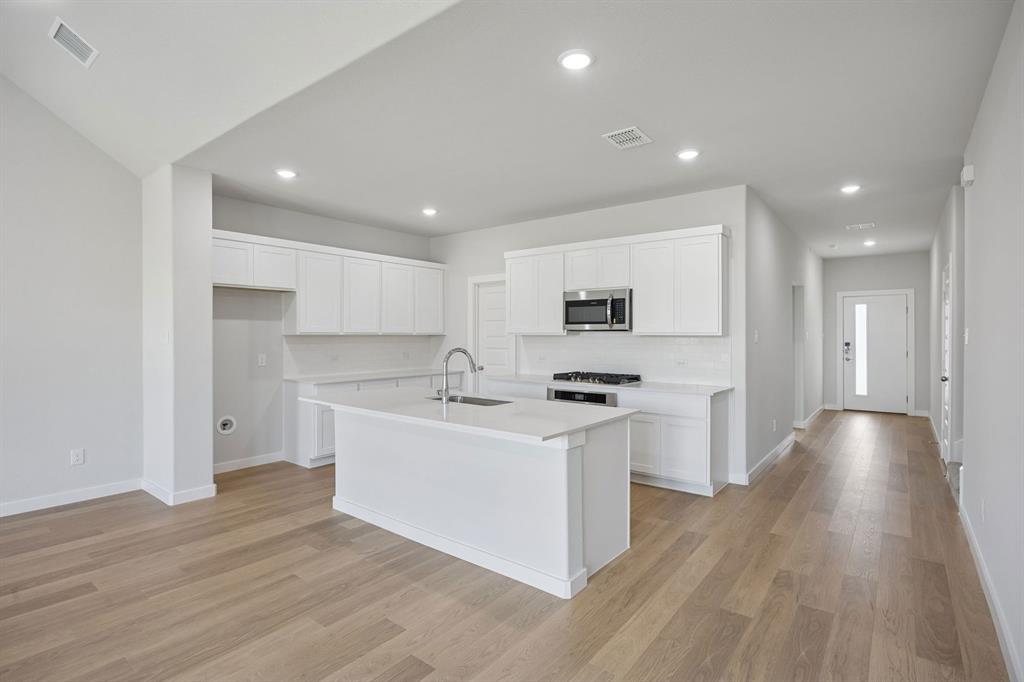 1472 Companero Street Haslet, TX 76052 - Photo 9 of 40 a kitchen with stainless steel appliances a sink stove and wooden floor