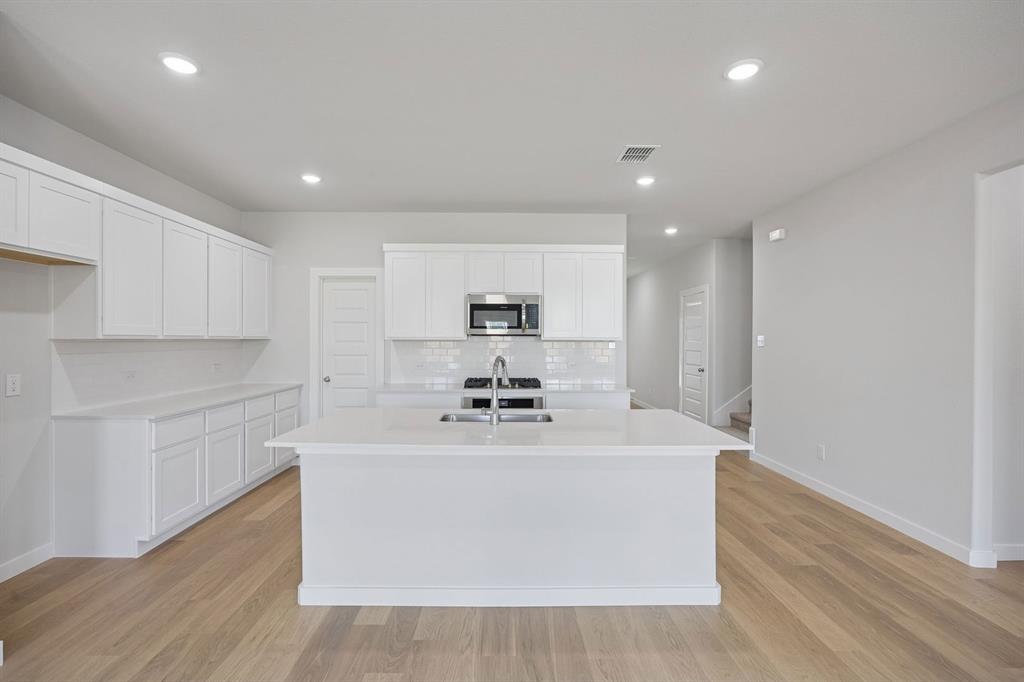 1472 Companero Street Haslet, TX 76052 - Photo 10 of 40 a large white kitchen with kitchen island a sink stainless steel appliances and white cabinets