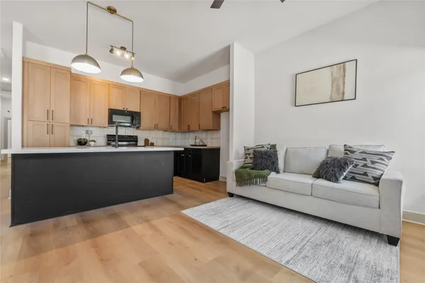 a kitchen with stainless steel appliances kitchen island granite countertop a refrigerator a sink dishwasher a stove and white cabinets with wooden floor