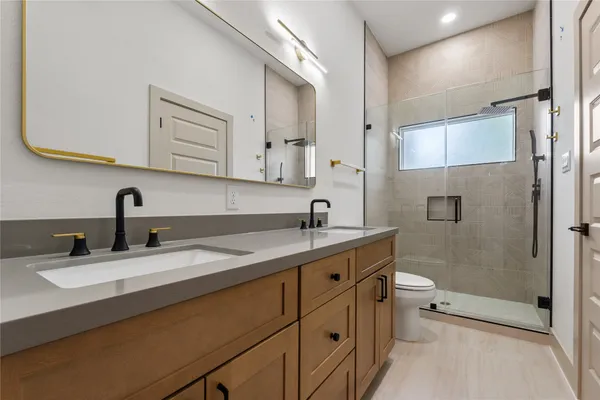 a bathroom with a double vanity sink toilet and mirror