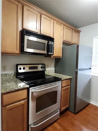 a kitchen with stainless steel appliances granite countertop a stove microwave refrigerator and cabinets