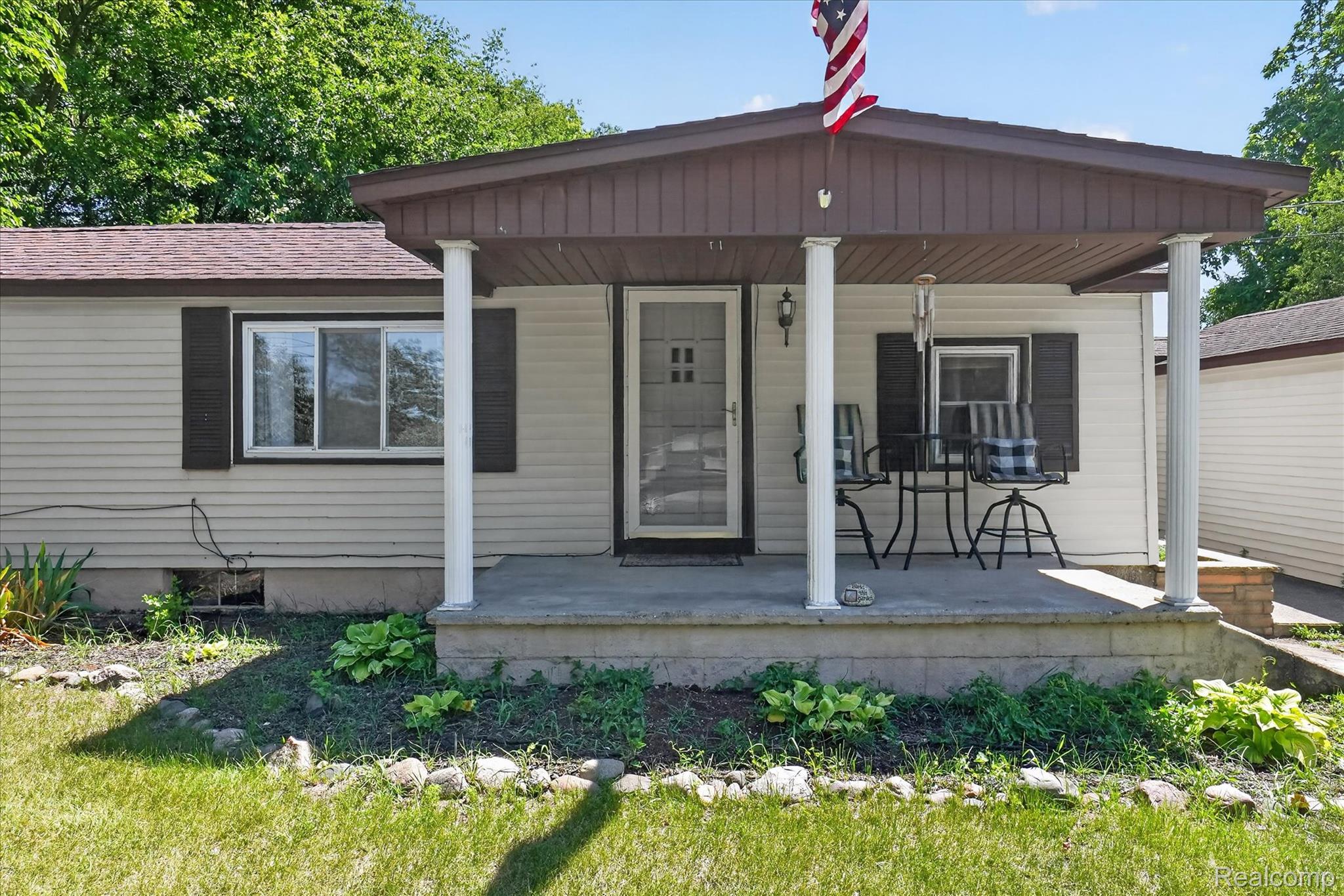 508 Deland Road Flushing, MI 48433 - Photo 4 of 38 Siding exterior with a covered front porch featuring white support columns and a brown roof