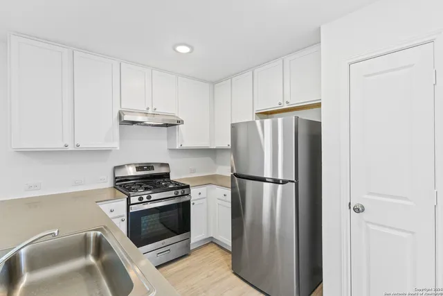 a kitchen with refrigerator a stove a sink and cabinets