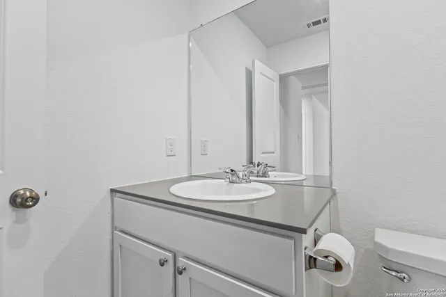 a bathroom with a granite countertop sink a toilet and mirror