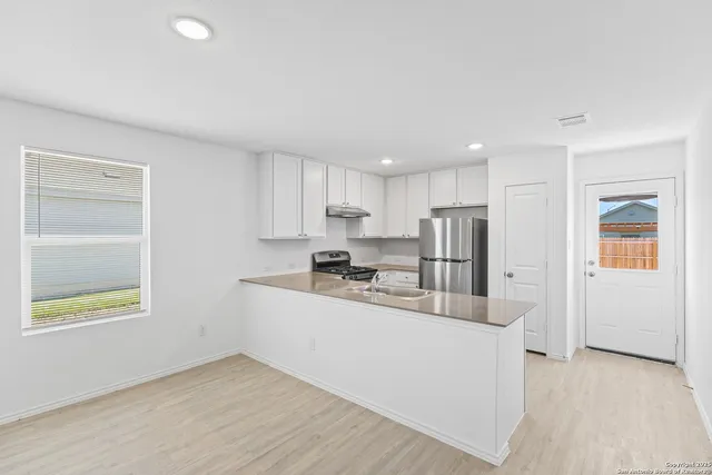 a kitchen with stainless steel appliances granite countertop a sink and a refrigerator