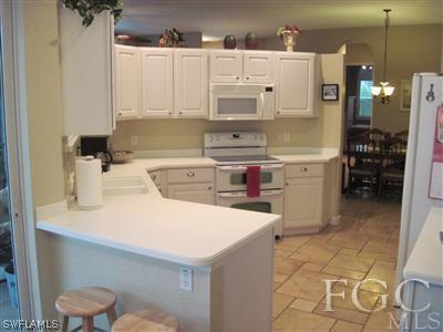 6119 Manchester Place Naples, FL 34110 - Photo 7 of 10 a kitchen with a sink a stove a refrigerator and cabinets