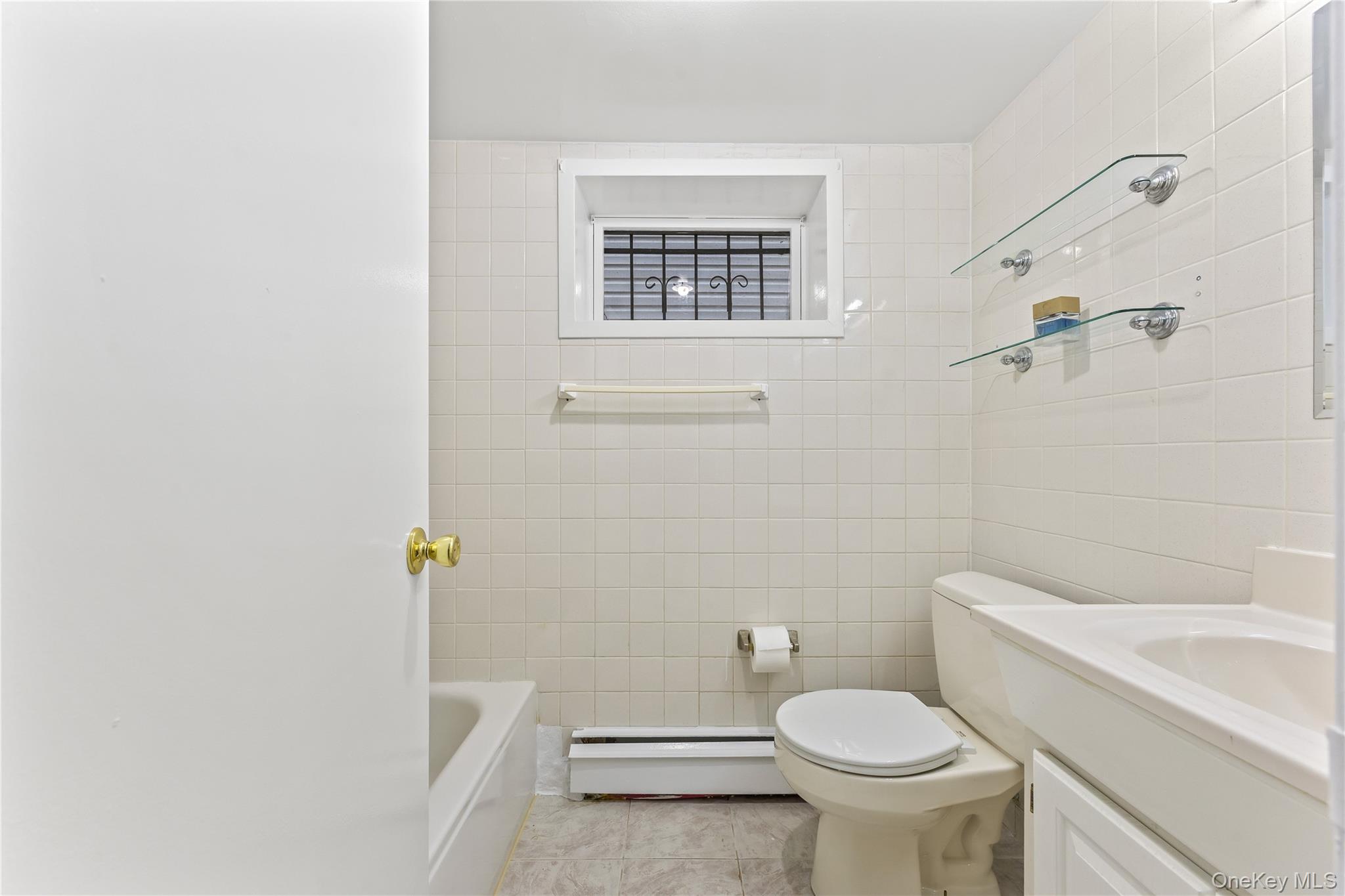 91-49 86th Street Queens, NY 11421 - Photo 34 of 42 a white toilet sitting next to a bathroom sink and tub