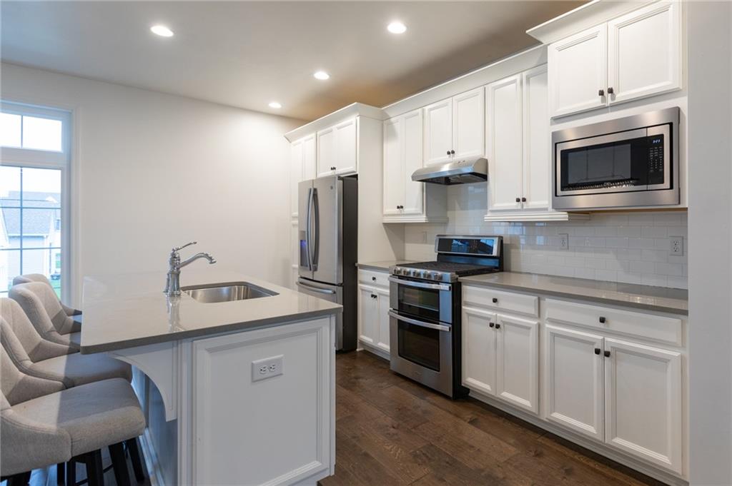 107 Gress Road Cranberry Township, PA 16066 - Photo 11 of 23 This bright, modern kitchen is designed to impress, featuring crisp white cabinetry that extends to the ceiling for a clean, timeless look and ample storage. A large center island with a sleek undermount sink provides generous prep space and casual seating, making it perfect for everyday living and entertaining alike. Stainless steel appliances, including a gas range, built-in microwave, and French-door refrigerator, pair beautifully with the glossy subway tile backsplash and smooth, neutral countertops.