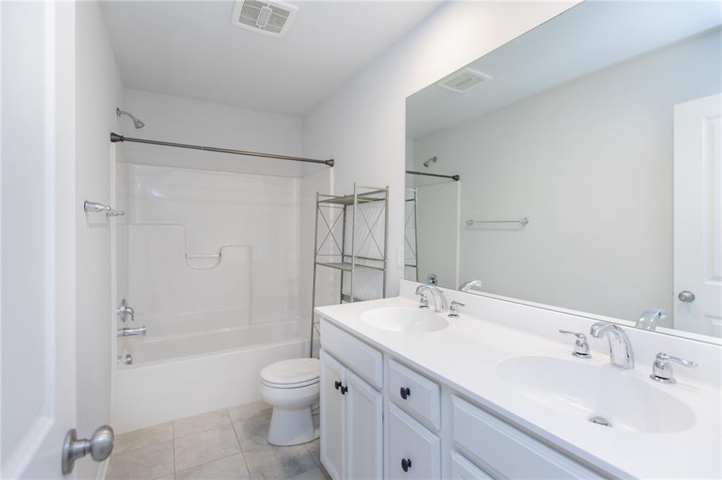 107 Gress Road Cranberry Township, PA 16066 - Photo 16 of 23 hall bath is bright, spacious, and thoughtfully designed to serve both comfort and functionality. A double bowl vanity with generous counter space and classic white cabinetry provides convenience for shared use, while the large wall-to-wall mirror reflects light and makes the room feel open and airy.